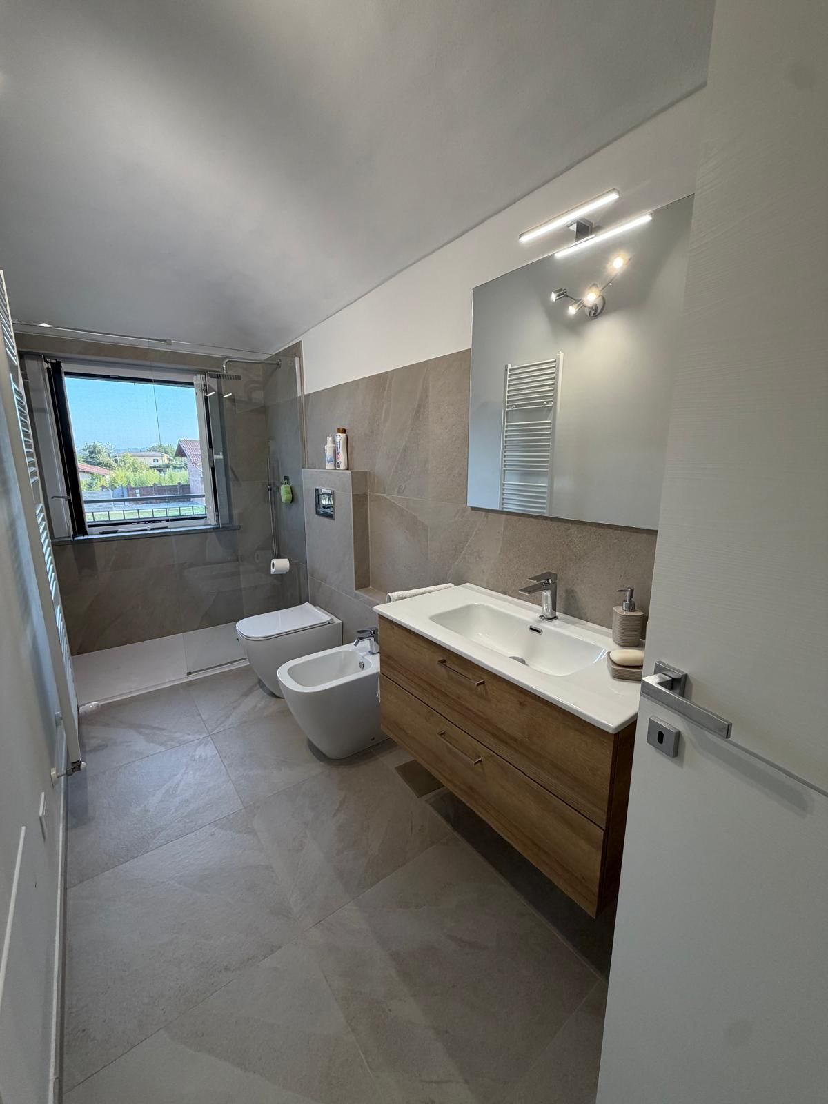 Bagno nuovo con mobile in legno, bidet e doccia